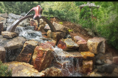 Inspiration for a large rustic full sun backyard stone water fountain landscape in Denver.