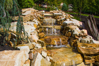 Photo of a mid-sized full sun hillside water fountain landscape in Other for summer.