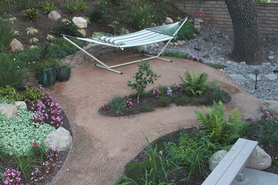 This is an example of a medium sized rustic back xeriscape fully shaded garden in Los Angeles with decomposed granite.
