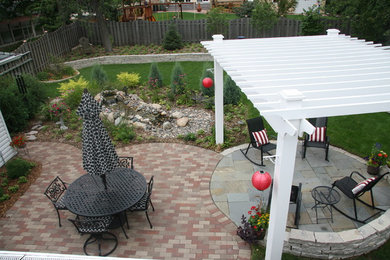 Large traditional back formal full sun garden in Minneapolis with natural stone paving and a retaining wall.