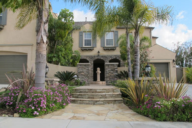 This is an example of a large mediterranean front formal full sun garden in San Diego with natural stone paving.