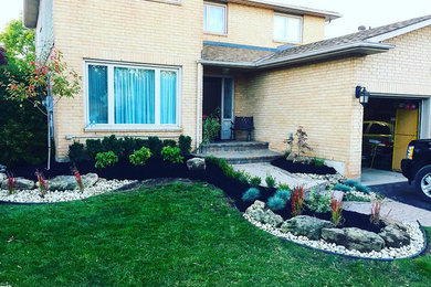This is an example of a small traditional full sun front yard mulch formal garden in Toronto for summer.