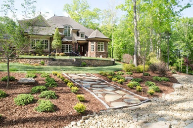 This is an example of a large traditional partial sun front yard stone retaining wall landscape in Raleigh.