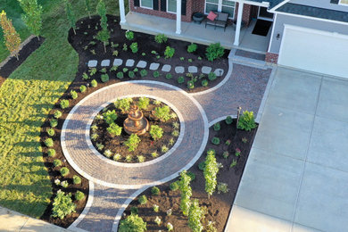 Diseño de jardín clásico de tamaño medio en verano en patio delantero con jardín francés, fuente, exposición parcial al sol y adoquines de hormigón