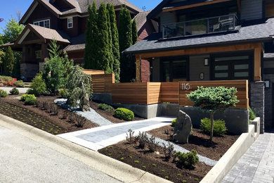 Photo of a mid-sized modern partial sun front yard stone retaining wall landscape in Vancouver.
