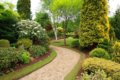 Inspiration för mellanstora klassiska formella trädgårdar i delvis sol framför huset på våren, med en trädgårdsgång och grus