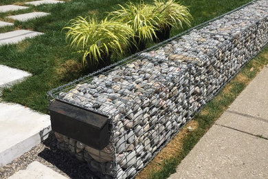 Photo of a mid-sized modern partial sun front yard concrete paver retaining wall landscape in Toronto.