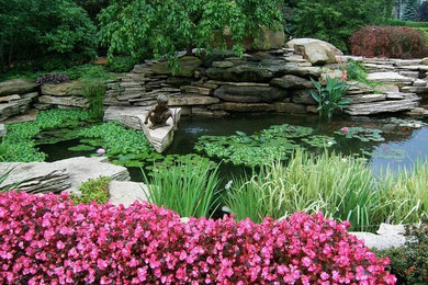 Photo of a medium sized classic back formal full sun garden for spring in Detroit with a pond and natural stone paving.
