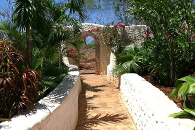 Immagine di un ampio giardino tropicale esposto a mezz'ombra in cortile in estate con pavimentazioni in pietra naturale