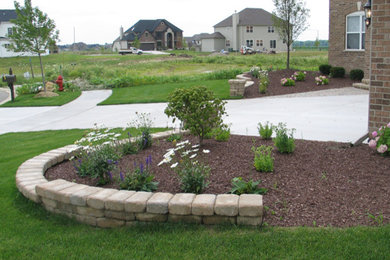 This is an example of a mid-sized front yard stone retaining wall landscape in Chicago.
