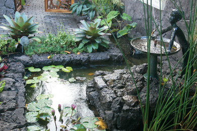 На фото: большой сад с прудом на заднем дворе в морском стиле с полуденной тенью и мощением тротуарной плиткой