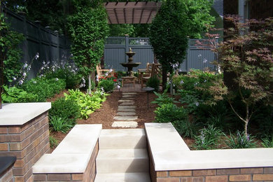 Aménagement d'un petit jardin classique au printemps avec une exposition ombragée et des pavés en pierre naturelle.
