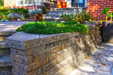 Photo of a mid-sized front yard concrete paver retaining wall landscape in Omaha.