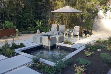 This is an example of a mid-sized transitional partial sun backyard concrete paver water fountain landscape in Los Angeles.