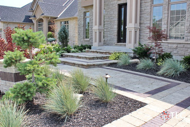 This is an example of a mid-sized traditional partial sun front yard brick landscaping in Toronto.