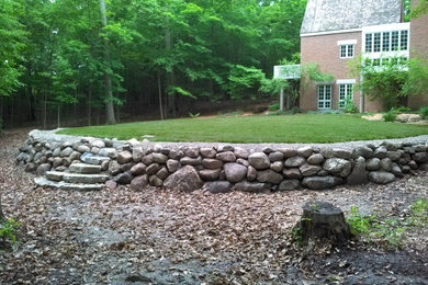 Photo of a mid-sized shade backyard stone retaining wall landscape in Detroit.