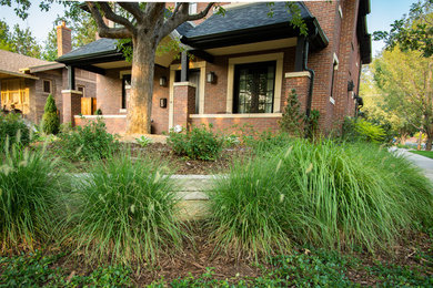 Idéer för mellanstora funkis trädgårdar framför huset, med en stödmur och naturstensplattor