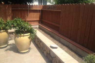 This is an example of a mid-sized partial sun backyard stone retaining wall landscape in Sacramento.