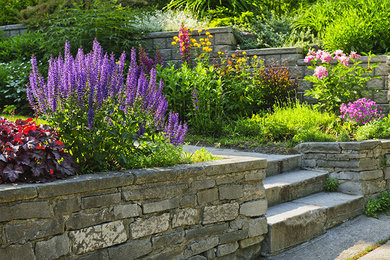 Ejemplo de jardín tradicional de tamaño medio en patio trasero con muro de contención, exposición parcial al sol y adoquines de piedra natural
