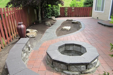 Example of a backyard brick patio design in Seattle with a fire pit