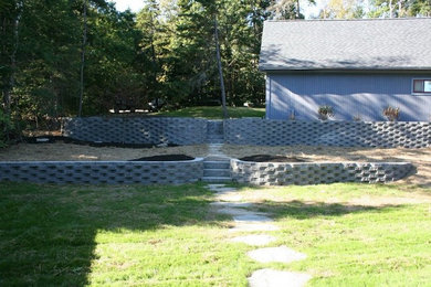 Ejemplo de jardín en patio trasero con muro de contención y adoquines de hormigón