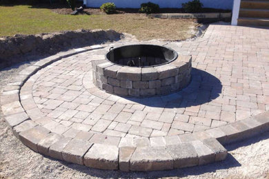 This is an example of a traditional backyard concrete paver landscaping in Other with a fire pit.