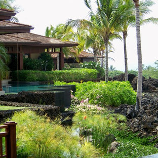 This is an example of a mid-sized tropical full sun backyard stone retaining wall landscape in Hawaii.