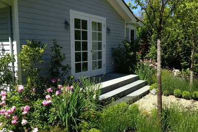 Imagen de jardín clásico grande en patio delantero con jardín francés, exposición parcial al sol y adoquines de piedra natural