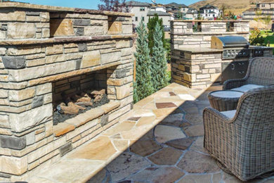 This is an example of a mid-sized contemporary backyard stone landscaping in Denver with a fireplace.