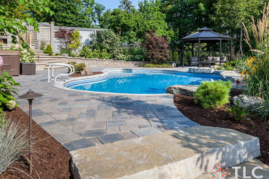 This is an example of a large traditional partial sun backyard concrete paver landscaping in Toronto.