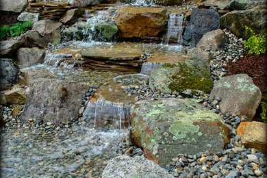Design ideas for a mid-sized rustic full sun hillside gravel water fountain landscape in New York.