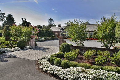 Imagen de jardín clásico extra grande en primavera en patio delantero con exposición total al sol y adoquines de hormigón