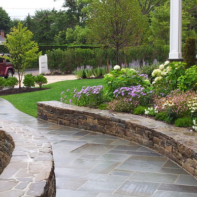 Inspiration for a mid-sized traditional partial sun front yard stone landscaping in Other.