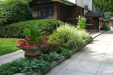 Стильный дизайн: большой участок и сад на переднем дворе в классическом стиле с растениями в контейнерах, полуденной тенью и покрытием из каменной брусчатки - последний тренд