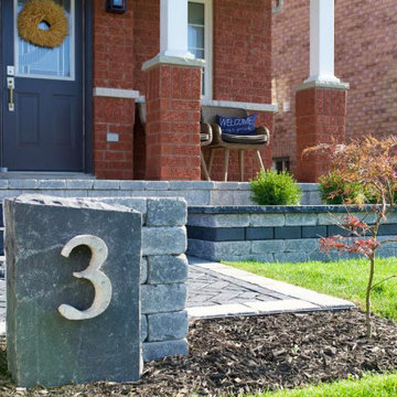 Inviting front entrance with natural stone steps, an elevated garden bed and a 1