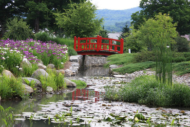 Imagen de jardín tradicional grande en patio trasero con fuente y adoquines de piedra natural