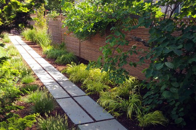 Small world-inspired back partial sun garden in Newark with a garden path and natural stone paving.