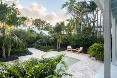 Inspiration för en mellanstor tropisk formell trädgård i full sol framför huset, med en fontän och naturstensplattor