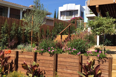 Modelo de jardín mediterráneo grande en verano en patio delantero con jardín francés, muro de contención, exposición total al sol, entablado y con madera