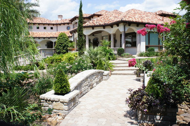 This is an example of a mid-sized mediterranean partial sun side yard stone landscaping in Houston for spring.