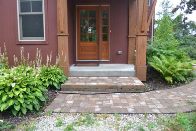 Photo of a mid-sized rustic front yard stone landscaping in Milwaukee.