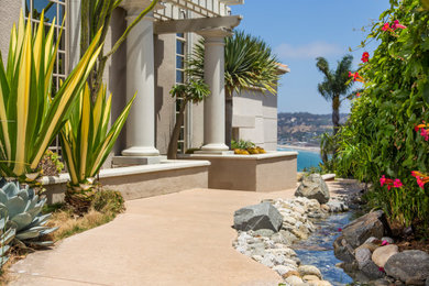 Photo of a mid-sized coastal partial sun courtyard river rock landscaping in San Diego for summer.