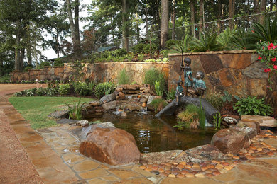 Modelo de jardín mediterráneo pequeño en verano en patio trasero con estanque y adoquines de piedra natural