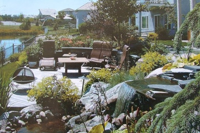 This is an example of a mid-sized transitional drought-tolerant and full sun hillside water fountain landscape in Edmonton with decking for summer.