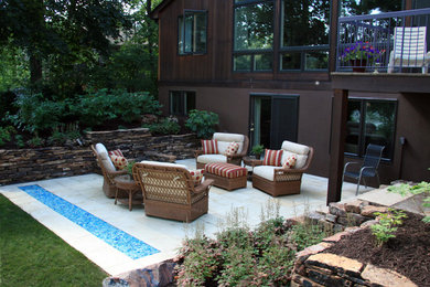 Réalisation d'une terrasse arrière chalet avec un foyer extérieur et des pavés en pierre naturelle.