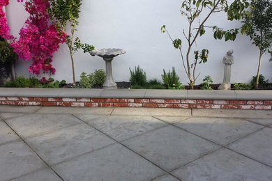 Modelo de jardín clásico de tamaño medio en patio delantero con jardín de macetas, exposición reducida al sol y adoquines de ladrillo