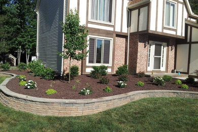 This is an example of a large traditional partial sun front yard stone landscaping in Cleveland.