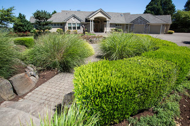 This is an example of a large traditional front driveway full sun garden in Portland with a garden path and concrete paving.