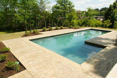Pool fountain - large backyard concrete paver pool fountain idea in Austin