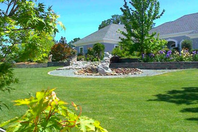 Diseño de jardín grande en patio trasero con exposición total al sol y adoquines de piedra natural